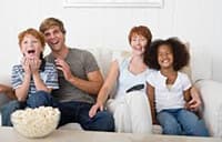 Family sitting on a couch eating popcorn and having fun.