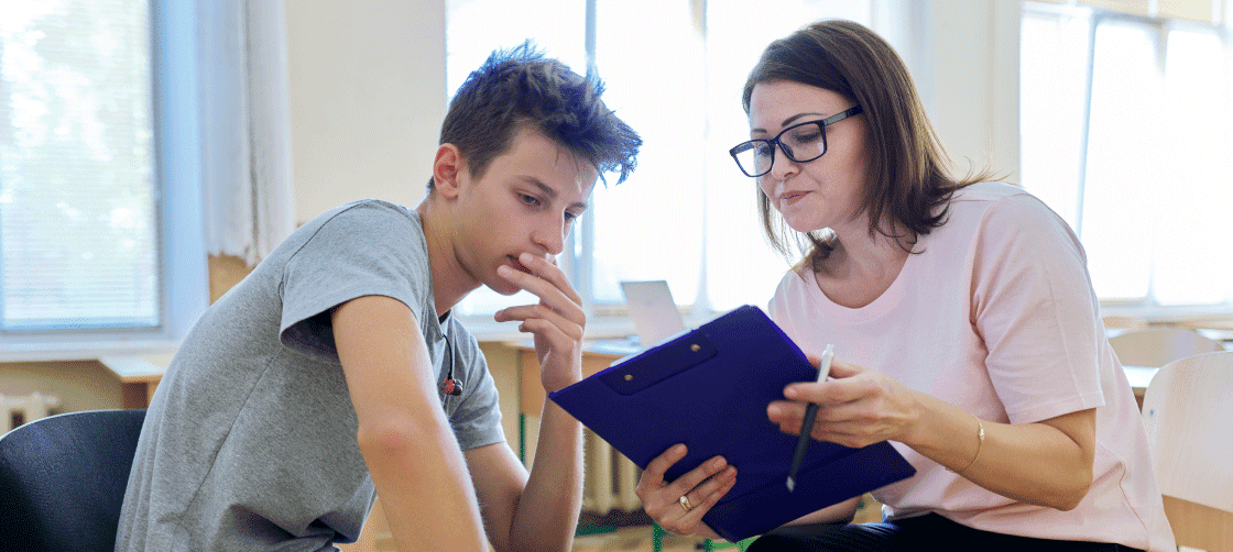 Woman showing an adolescent what's on her clipboard