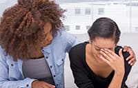 A woman consoling another woman who is crying